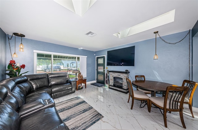 living room with a skylight, light tile patterned flooring, and a stone fireplace