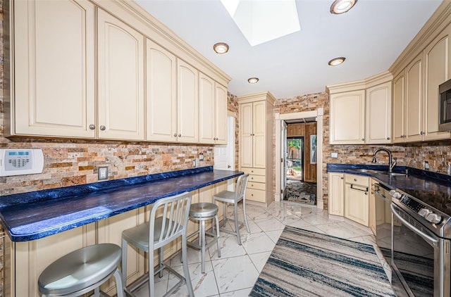 kitchen with a skylight, light tile patterned floors, and cream cabinetry