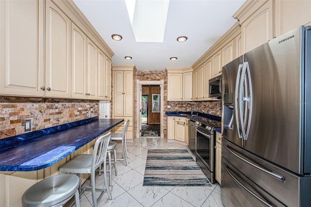 kitchen with a kitchen bar, backsplash, appliances with stainless steel finishes, and light tile patterned flooring