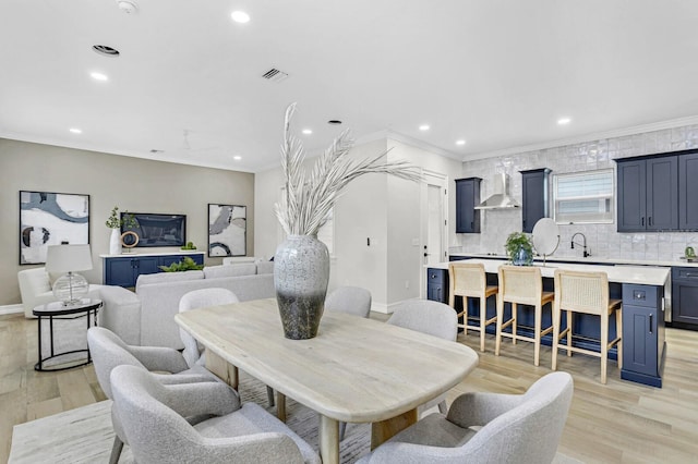 dining space featuring crown molding and light hardwood / wood-style flooring