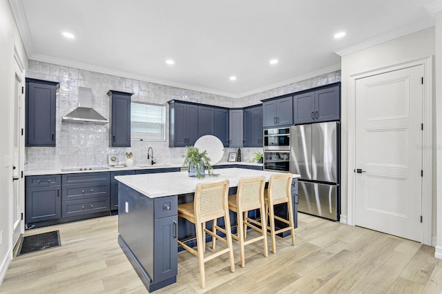 kitchen featuring a center island, wall chimney range hood, a breakfast bar area, light hardwood / wood-style flooring, and stainless steel appliances