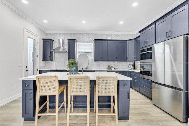 kitchen featuring stainless steel built in fridge, wall chimney range hood, light hardwood / wood-style flooring, a kitchen island with sink, and a breakfast bar