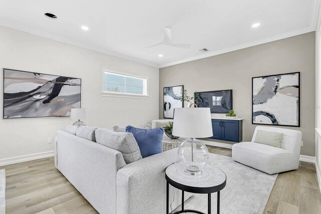 living room featuring ceiling fan, ornamental molding, and light wood-type flooring