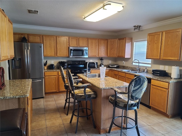 kitchen featuring crown molding, a kitchen bar, appliances with stainless steel finishes, a center island with sink, and light tile patterned flooring