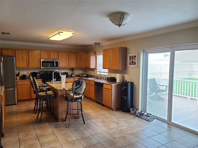 kitchen featuring a center island with sink, plenty of natural light, stainless steel appliances, and light stone countertops