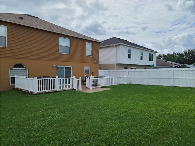 rear view of house featuring a yard and a deck