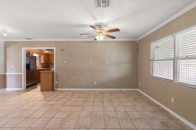 unfurnished room featuring ceiling fan, visible vents, baseboards, and ornamental molding