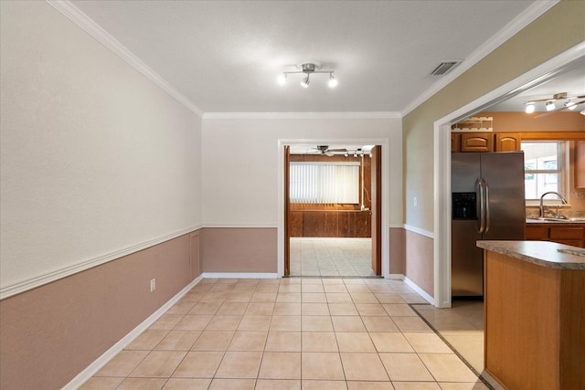 unfurnished dining area with crown molding, light tile patterned floors, visible vents, a ceiling fan, and a sink