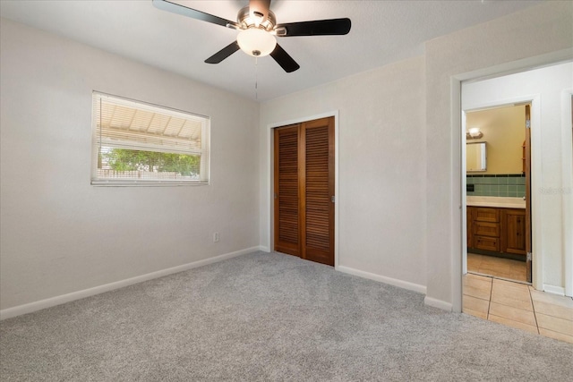 unfurnished bedroom featuring a closet, ceiling fan, connected bathroom, and light carpet