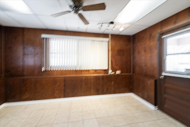 empty room featuring ceiling fan and wooden walls