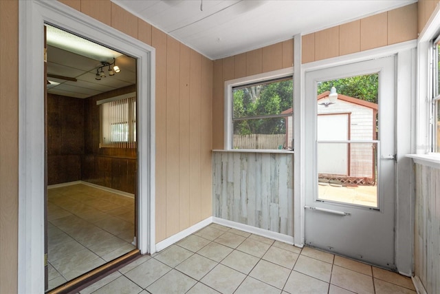 interior space with wood walls, light tile patterned flooring, and baseboards