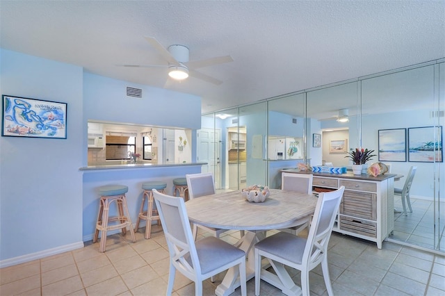 dining area featuring a textured ceiling, visible vents, a ceiling fan, and light tile patterned flooring