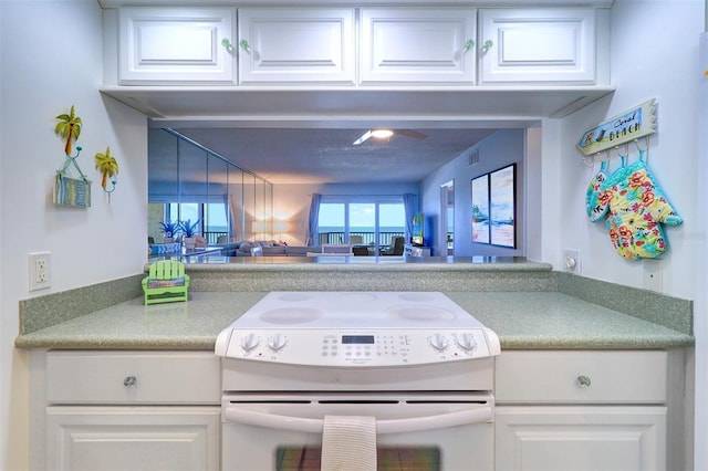 kitchen featuring visible vents, white electric range, and white cabinetry