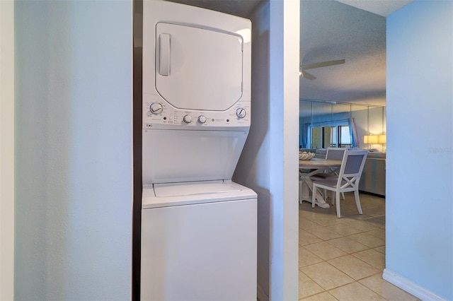 clothes washing area with light tile patterned floors, ceiling fan, laundry area, and stacked washer / dryer