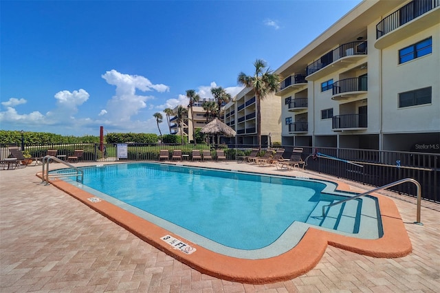 community pool with a patio area and fence