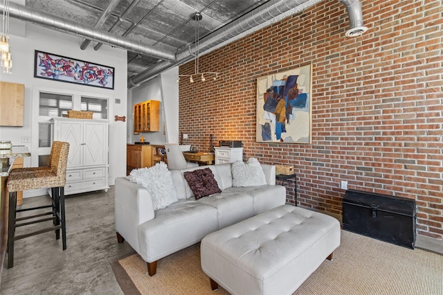 living room featuring concrete floors, a high ceiling, and brick wall