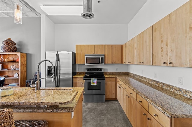 kitchen with appliances with stainless steel finishes, sink, stone counters, and pendant lighting