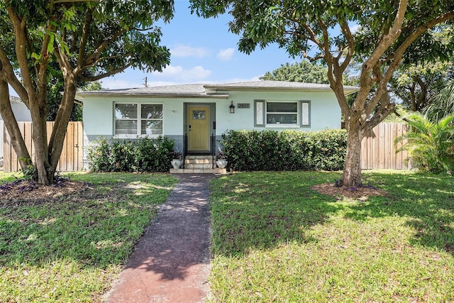 view of front of property with fence, a front lawn, and stucco siding