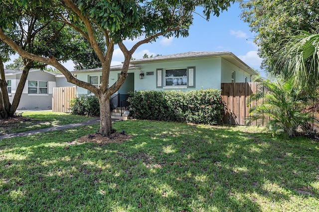 view of front of property featuring a front lawn, fence, and stucco siding