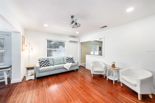 living room with a wall unit AC and hardwood / wood-style floors