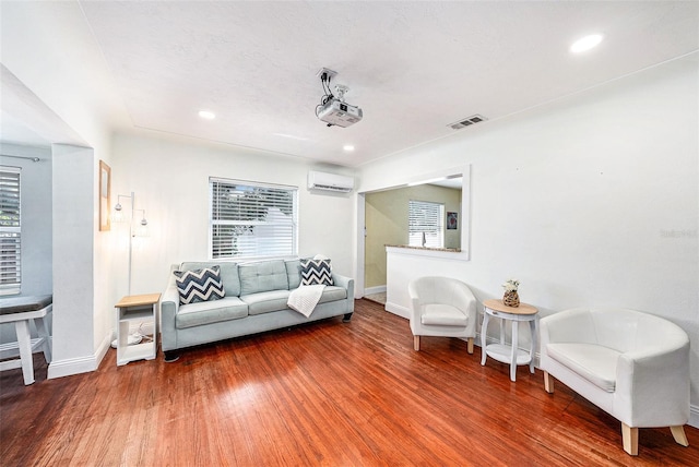 living area featuring recessed lighting, visible vents, an AC wall unit, wood finished floors, and baseboards