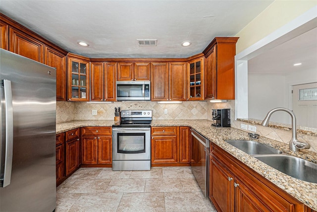 kitchen featuring stainless steel appliances, visible vents, glass insert cabinets, and a sink