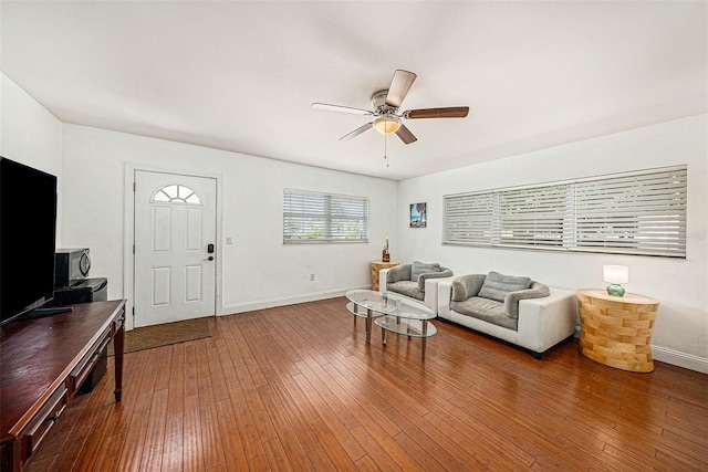 living area with a ceiling fan, baseboards, and hardwood / wood-style floors