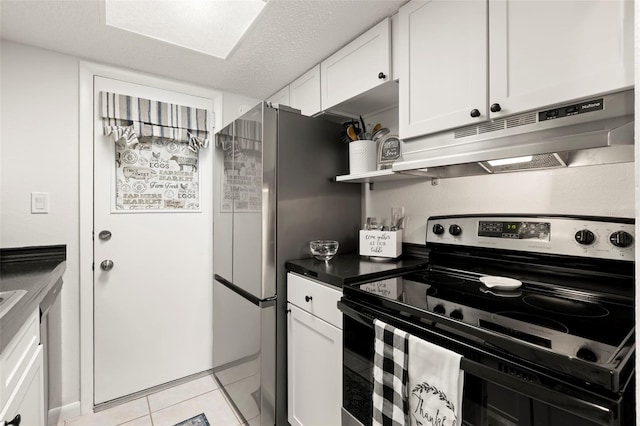 kitchen with appliances with stainless steel finishes, a textured ceiling, light tile patterned flooring, and white cabinets