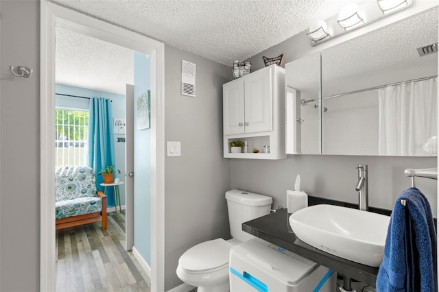 bathroom featuring toilet, hardwood / wood-style flooring, sink, and a textured ceiling