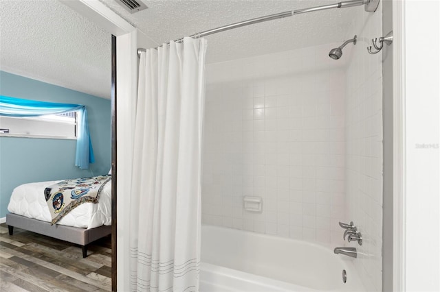 bathroom featuring a textured ceiling, wood-type flooring, and shower / bathtub combination with curtain