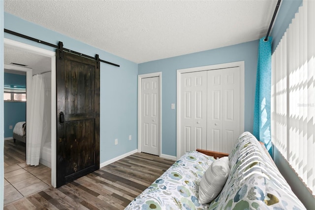 bedroom featuring a textured ceiling, a barn door, and dark hardwood / wood-style floors