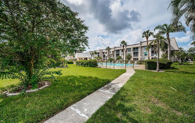 view of property's community with a swimming pool and a lawn