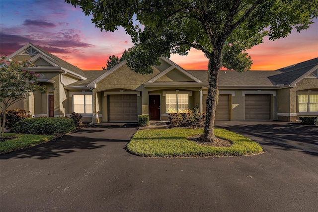 view of front facade with a garage, driveway, and stucco siding