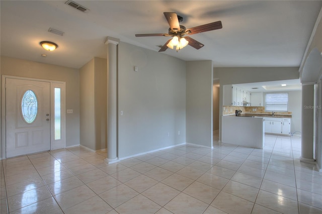 entrance foyer featuring lofted ceiling, ceiling fan, light tile patterned floors, and decorative columns