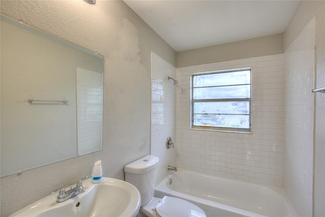 full bathroom featuring tiled shower / bath, toilet, and sink