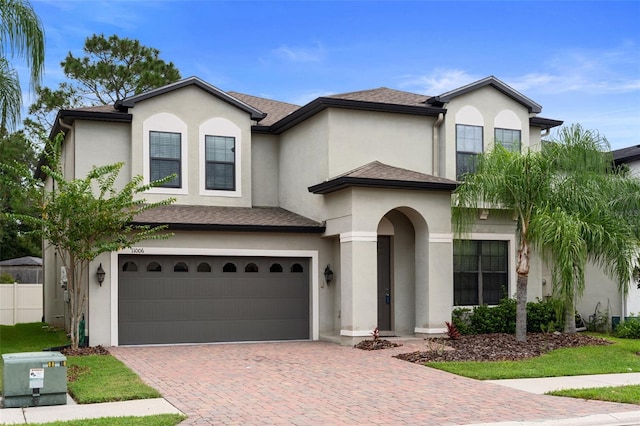 view of front of home featuring decorative driveway, stucco siding, a shingled roof, fence, and a garage