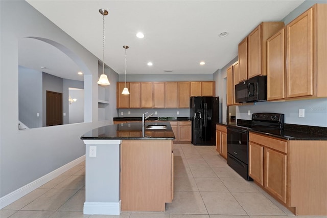 kitchen with a kitchen island with sink, dark stone countertops, pendant lighting, light tile patterned floors, and black appliances