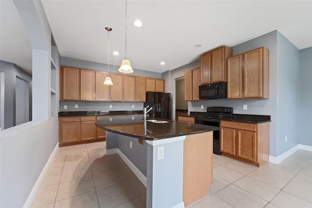 kitchen with dark stone countertops, decorative light fixtures, light tile patterned floors, black appliances, and a center island with sink