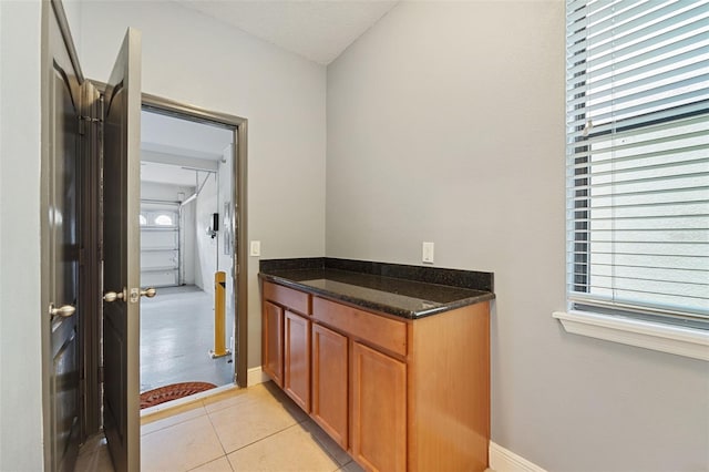 kitchen with light tile patterned floors and dark stone counters