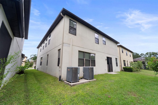 rear view of property featuring central AC and a lawn