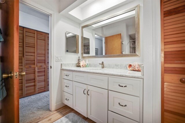 bathroom featuring hardwood / wood-style floors, a skylight, and vanity