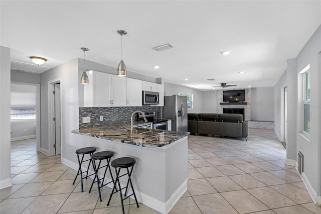 kitchen featuring kitchen peninsula, appliances with stainless steel finishes, plenty of natural light, and decorative light fixtures