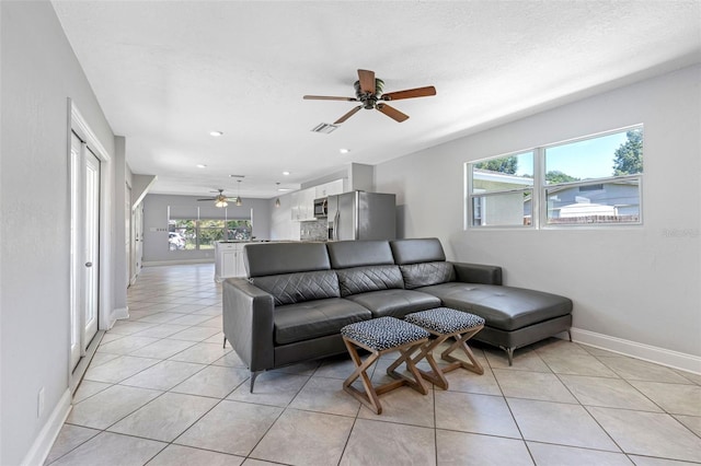 tiled living room featuring a textured ceiling, a healthy amount of sunlight, and ceiling fan