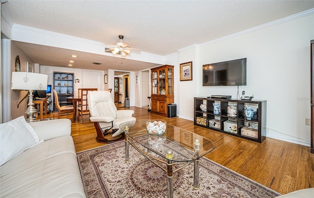 living room featuring ceiling fan, hardwood / wood-style flooring, crown molding, and a textured ceiling