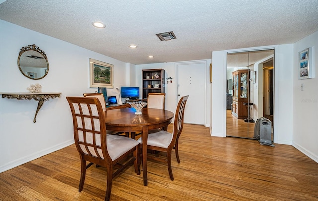 dining space with a textured ceiling and hardwood / wood-style floors