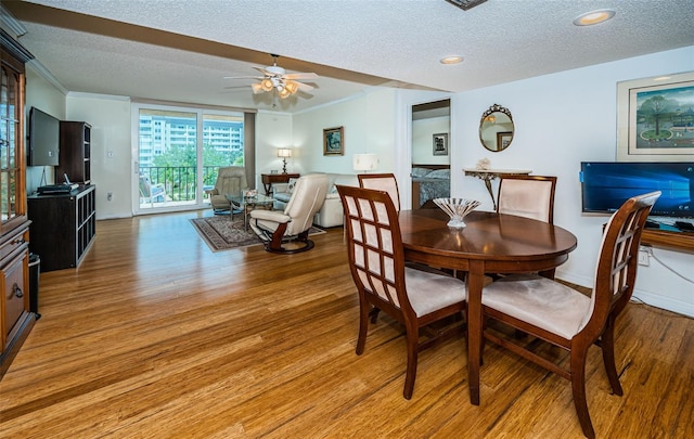 dining room featuring a textured ceiling, crown molding, ceiling fan, and wood-type flooring