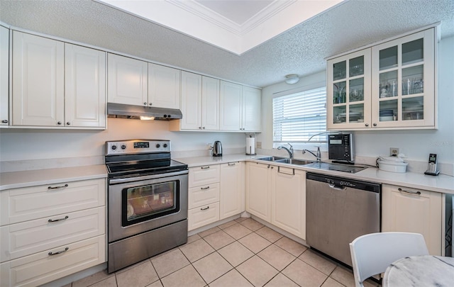 kitchen featuring white cabinets, light tile patterned floors, appliances with stainless steel finishes, ornamental molding, and a textured ceiling