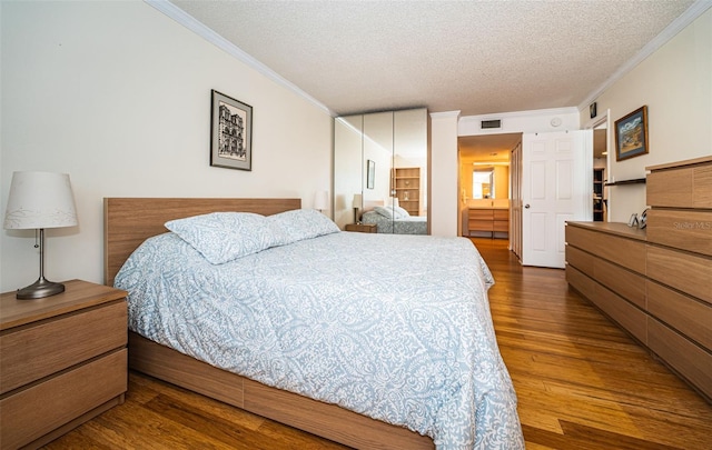 bedroom with a textured ceiling, ornamental molding, and wood-type flooring