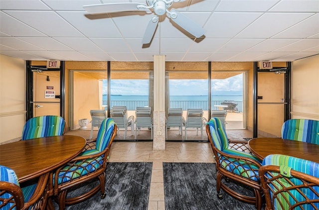 dining area featuring floor to ceiling windows, ceiling fan, a water view, and light tile patterned flooring