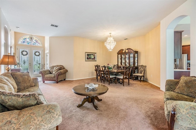 carpeted living room featuring french doors and a chandelier